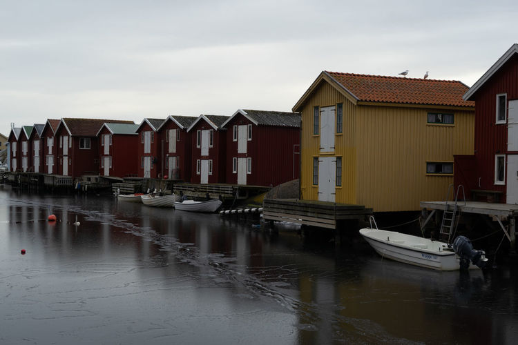 Boats moored in canal amidst buildings against sky