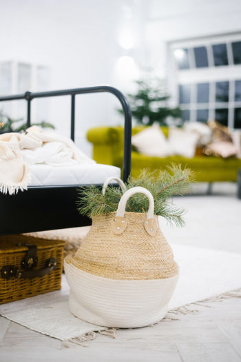 Bag with pine branches near the bed in the bedroom decor in scandinavian style