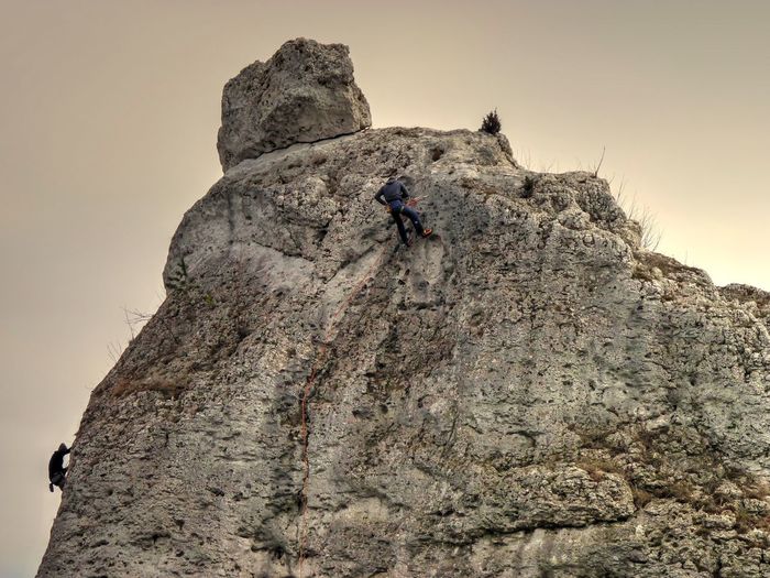 Low angle view of man climbing mountain against sky