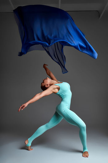 Full length of woman jumping against black background
