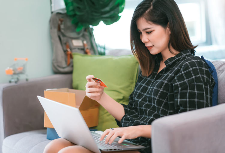 Woman doing online shopping over laptop on sofa