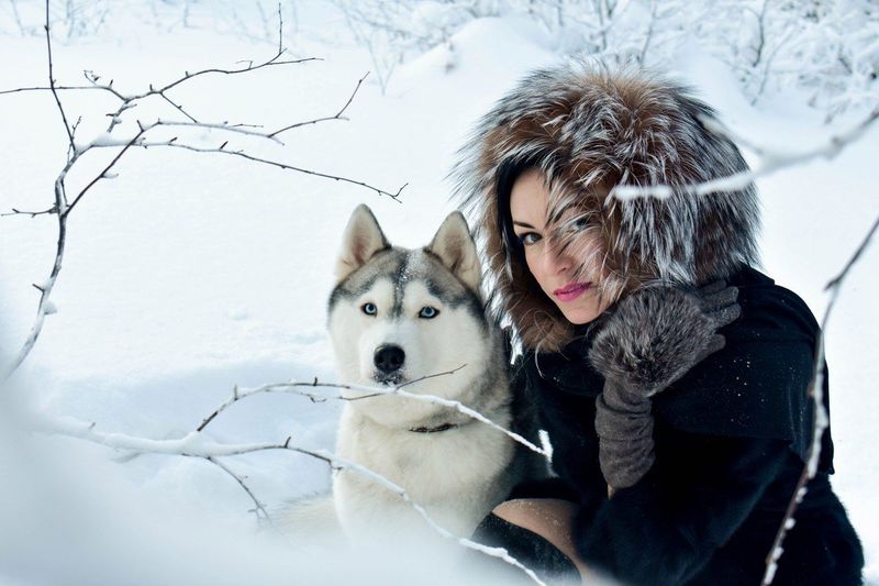 Portrait of young woman with dog in snow