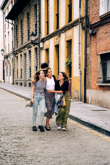 Meeting of young curly stylish women bonding and talking in city street