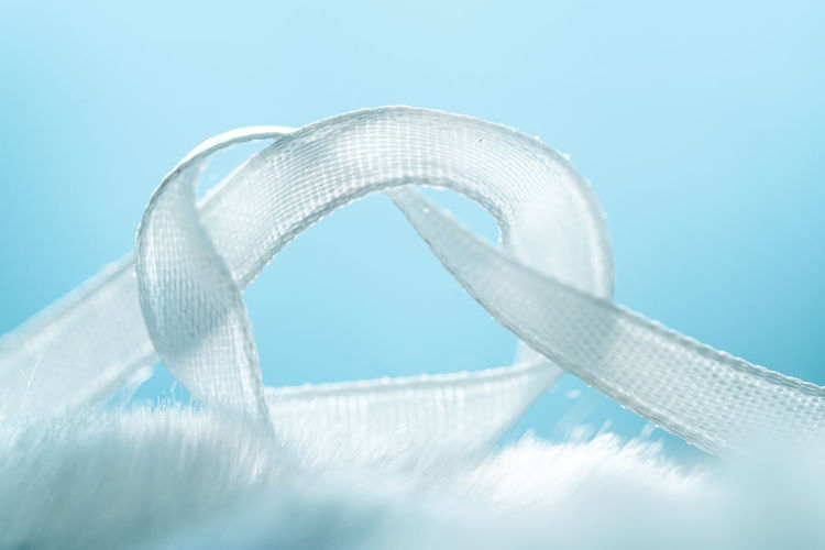 Close-up of a white satin ribbon on a blue background. not to forget concept
