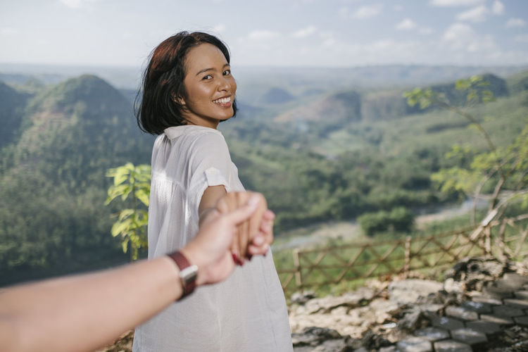 Cropped image of man holding woman hands on mountain