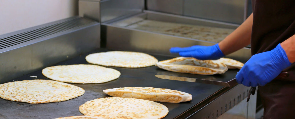 Cook with latex gloves cooking italian food called piadina romagnola on the plate