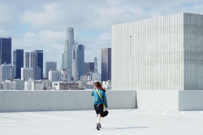 Rear view of woman walking against modern buildings