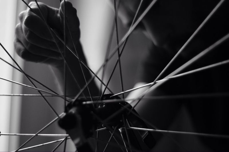 Cropped image of man seen through bicycle spokes