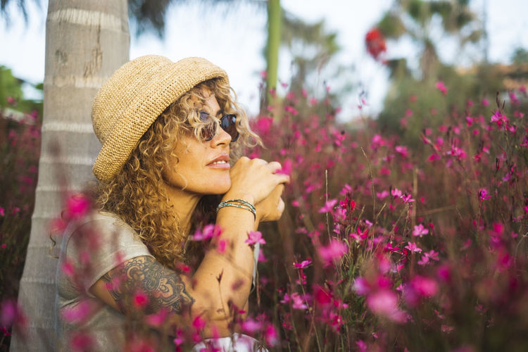 Portrait of young woman wearing sunglasses while standing against plants