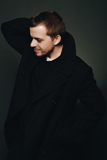 Young man standing against black background