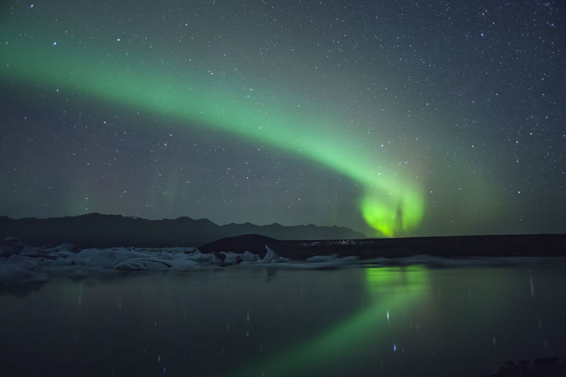 Scenic view of aurora borealis over lake against sky at night