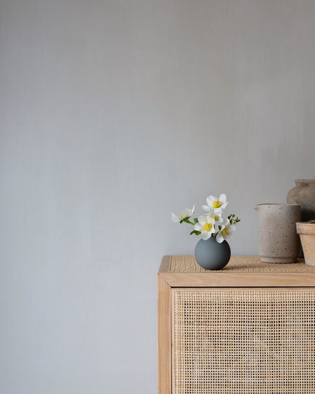 White flower vase on table against wall