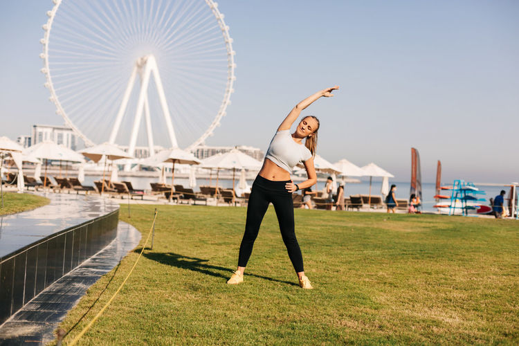 A beautiful woman does yoga on the background of the blue waters island in dubai.