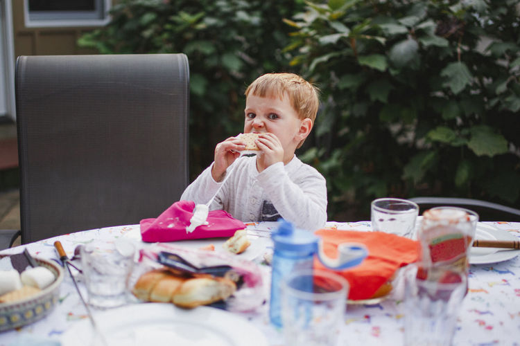 A small boy eats a messy s'more at an outdoor dinner table