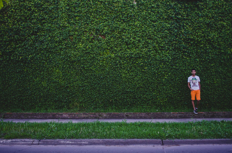 Man standing against wall covered with plants
