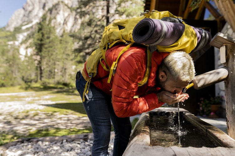Hiker with backpack drinking water from fountain