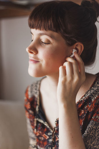 Young woman putting in wireless earphones