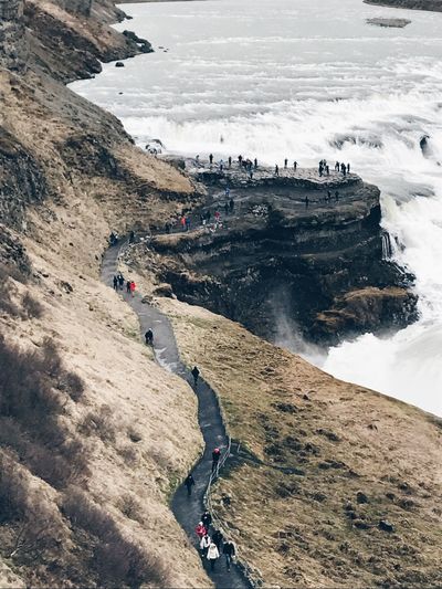 High angle view of people standing on footpath by mountain at gullfoss waterfall