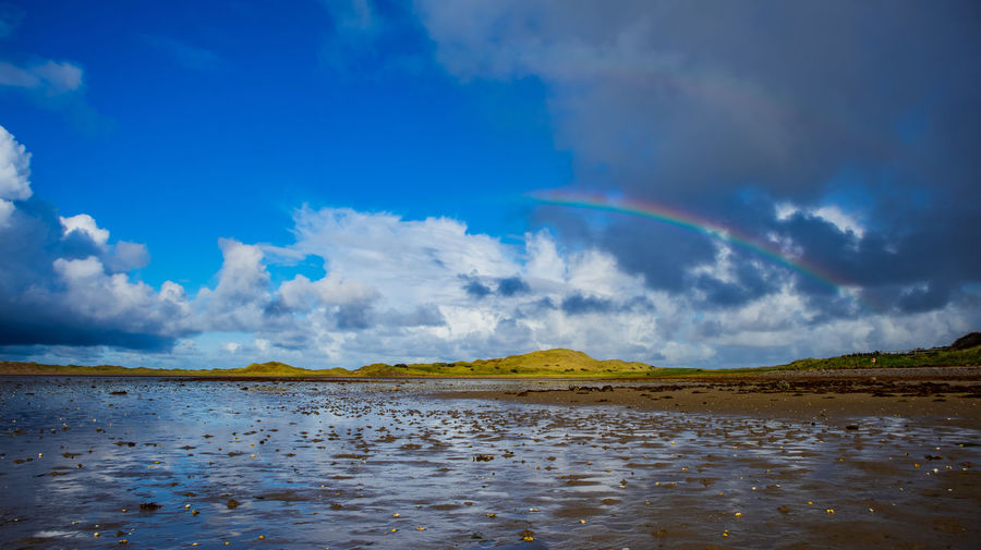 Scenic view of sea against rainbow in sky