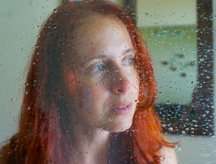 Portrait of woman with raindrops on window