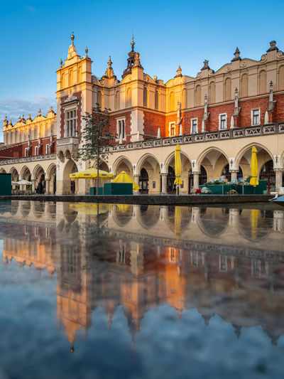 Reflections of cloth hall sukiennice building at sunrise on main square of krakow city, poland
