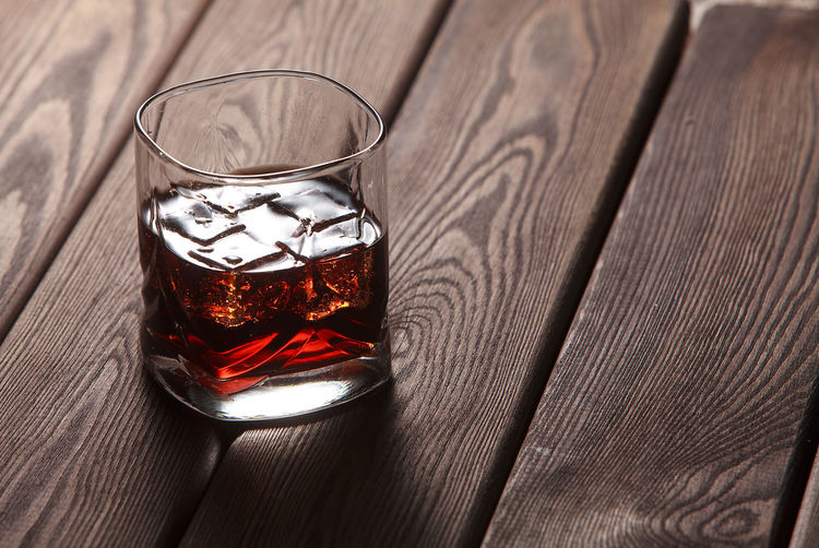 Whiskey in a glass with ice in a dark wooden background
