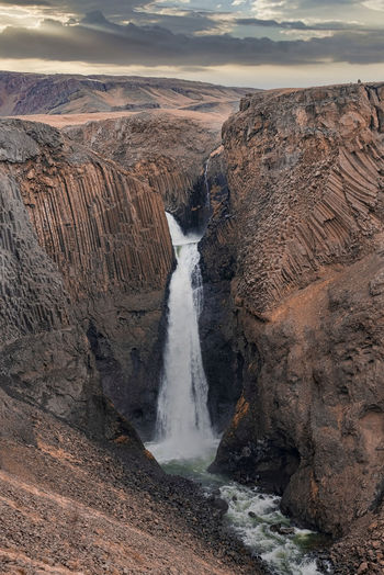 Idyllic litlanesfoss waterfall amidst basalt columns and stream against sky