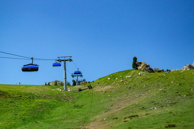 Overhead cable car on field against clear blue sky