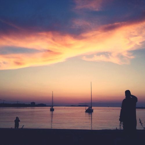Silhouette people standing on beach against sky during sunset
