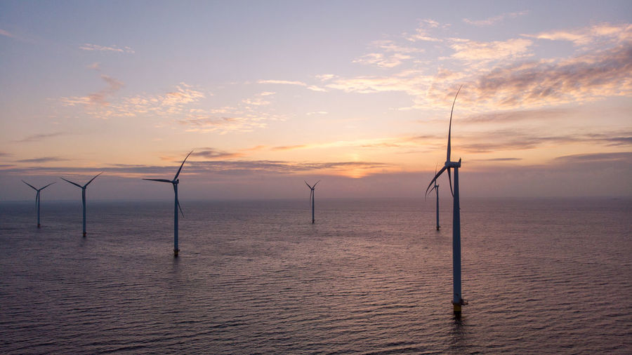 Wind turbines in sea against sky during sunset, windmill turbines in the netherlands 