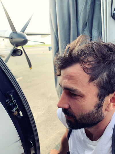 Close-up portrait of man looking at airplane