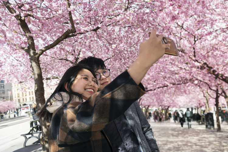 Couple taking selfie under cherry blossom