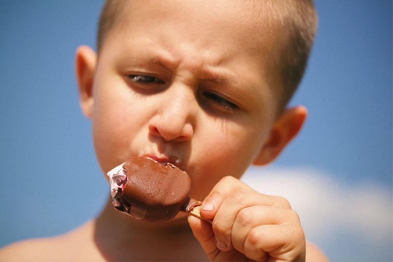 Portrait of cute boy eating ice cream against sky