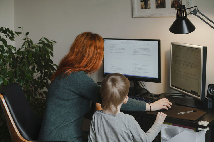 Woman working on computer while child looking and waiting for her attention. freelancer mother doing