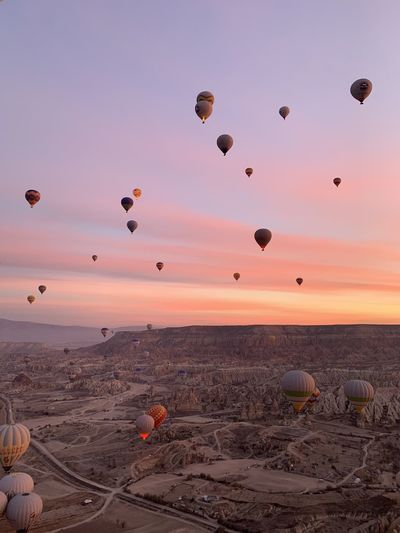 Hot air balloons flying over land during sunset