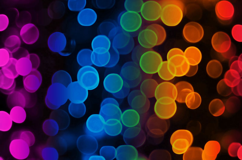 Defocused image of multi colored illuminated lights against black background