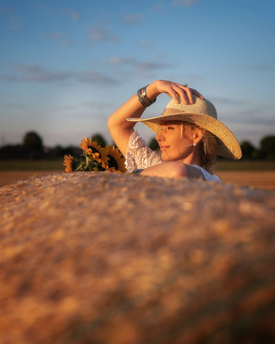 Portrait of woman wearing straw hat on field against sky