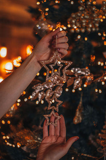 Cropped hand of woman holding illuminated christmas tree