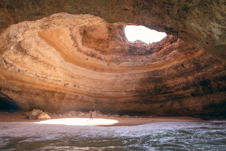 Surfer walking in cave by the sea
