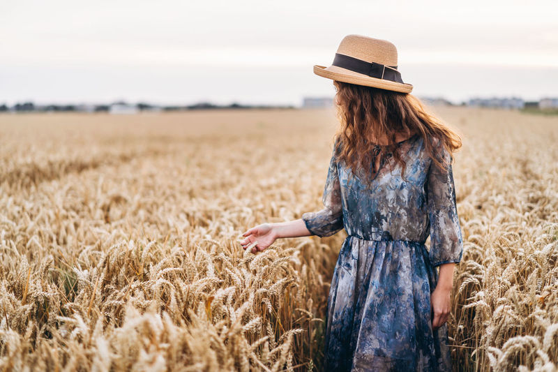 Woman wearing hat standing amidst crops in farm