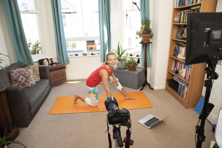 Fitness woman doing exercise video recording with camera at home