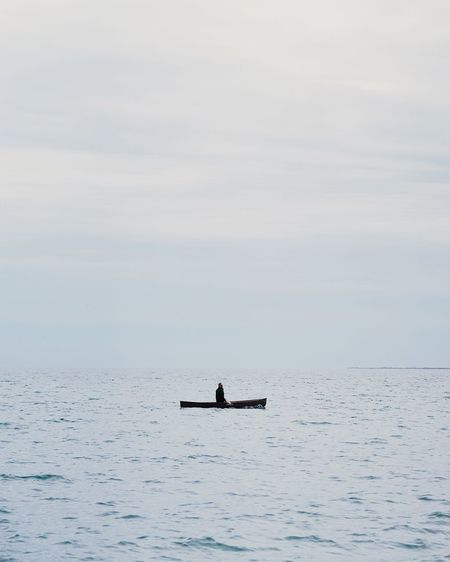 Man sailing on sea against sky