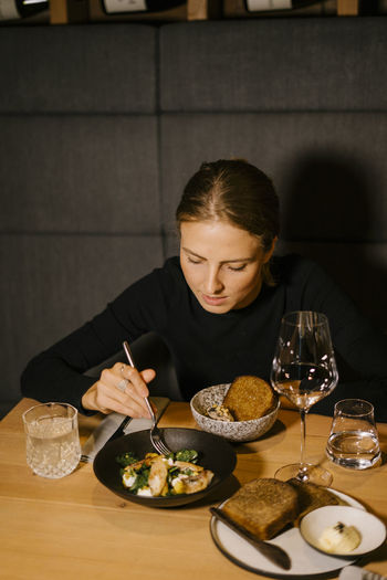 Young woman having meal at dining table in restaurant