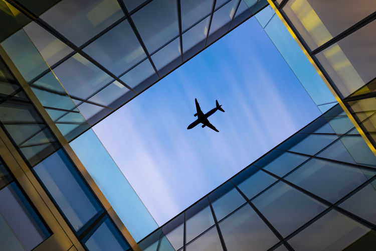 Directly below shot of building and airplane flying in sky