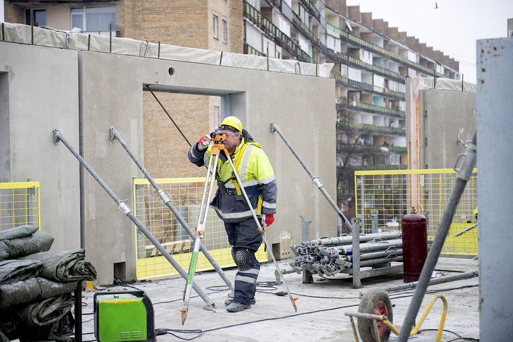 Surveyor worker working with theodolite transit equipment at construction site outdoors