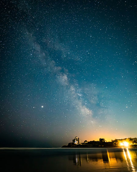 Milkyway galaxy and stars in the night sky above beach houses.
