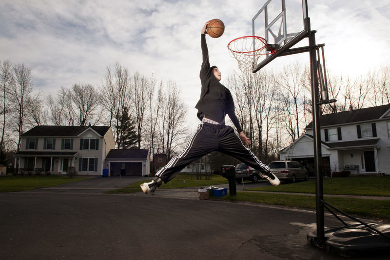 Boy dunking ball in hoop on road