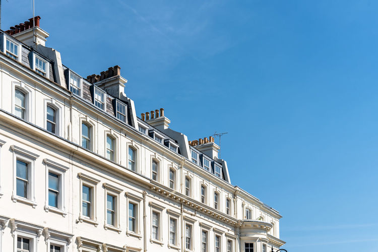 Luxury english victorian houses in notting hill in london against blue sky.