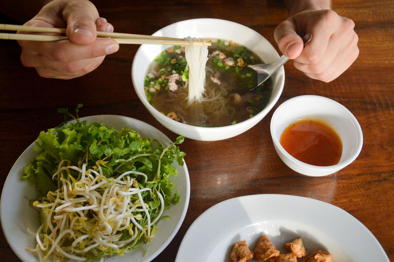 High angle view of man eating laotian noodle soup called khao piak sen