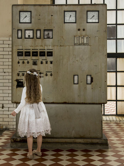 Rear view of girl standing against electric meter